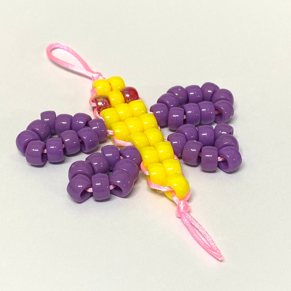 Colorful butterfly-shaped toy with purple wings and a yellow body on a white background