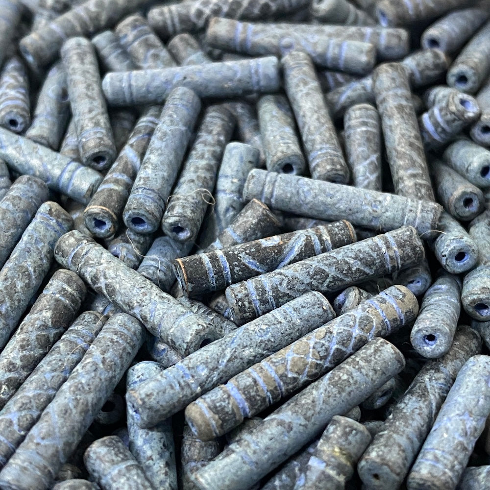 Close-up of a pile of blue cylindrical vintage ceramic beads with intricate patterns.
