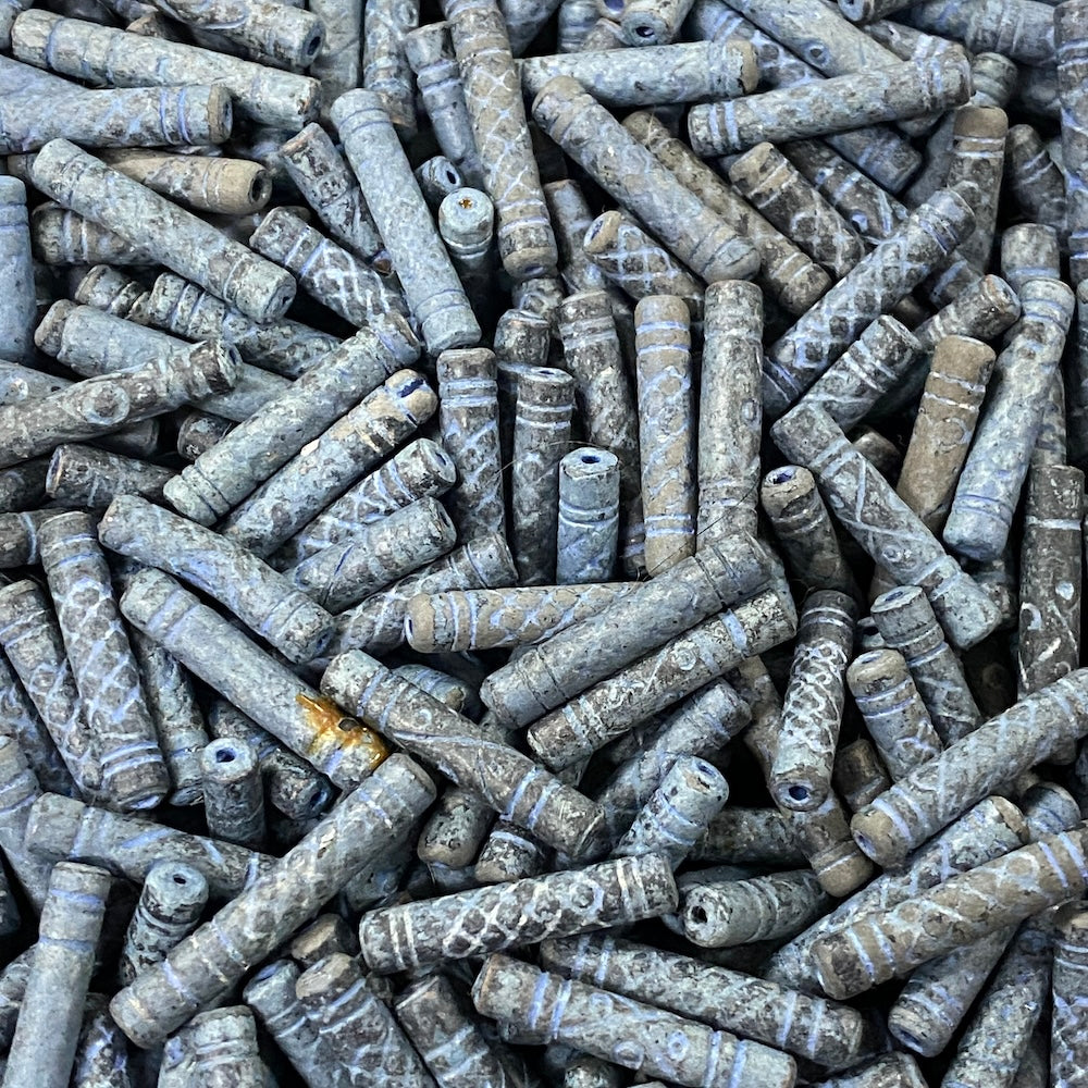 Close-up of a pile of blue cylindrical vintage ceramic beads with intricate patterns.