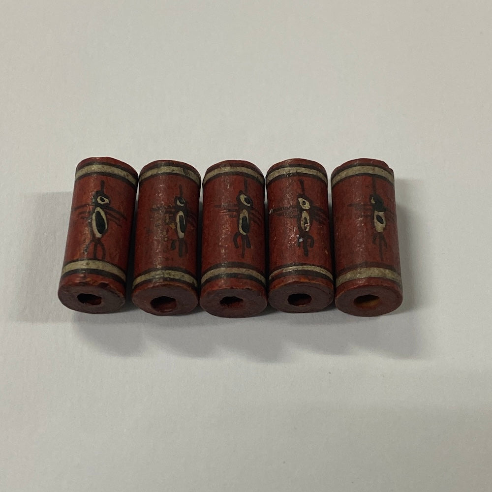 Five cylindrical old ceramic beads with decorative elements on a white background