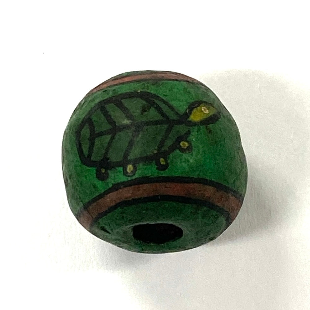 Green bead with a turtle design on a white background