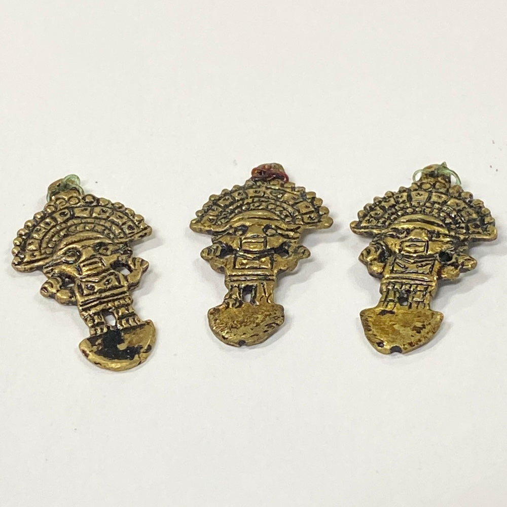 Three brass tumi figurines on a white background