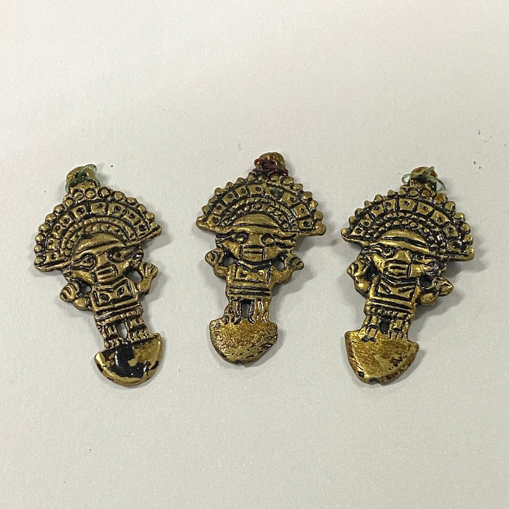 Three brass-colored tribal-style south american pendants on a white background