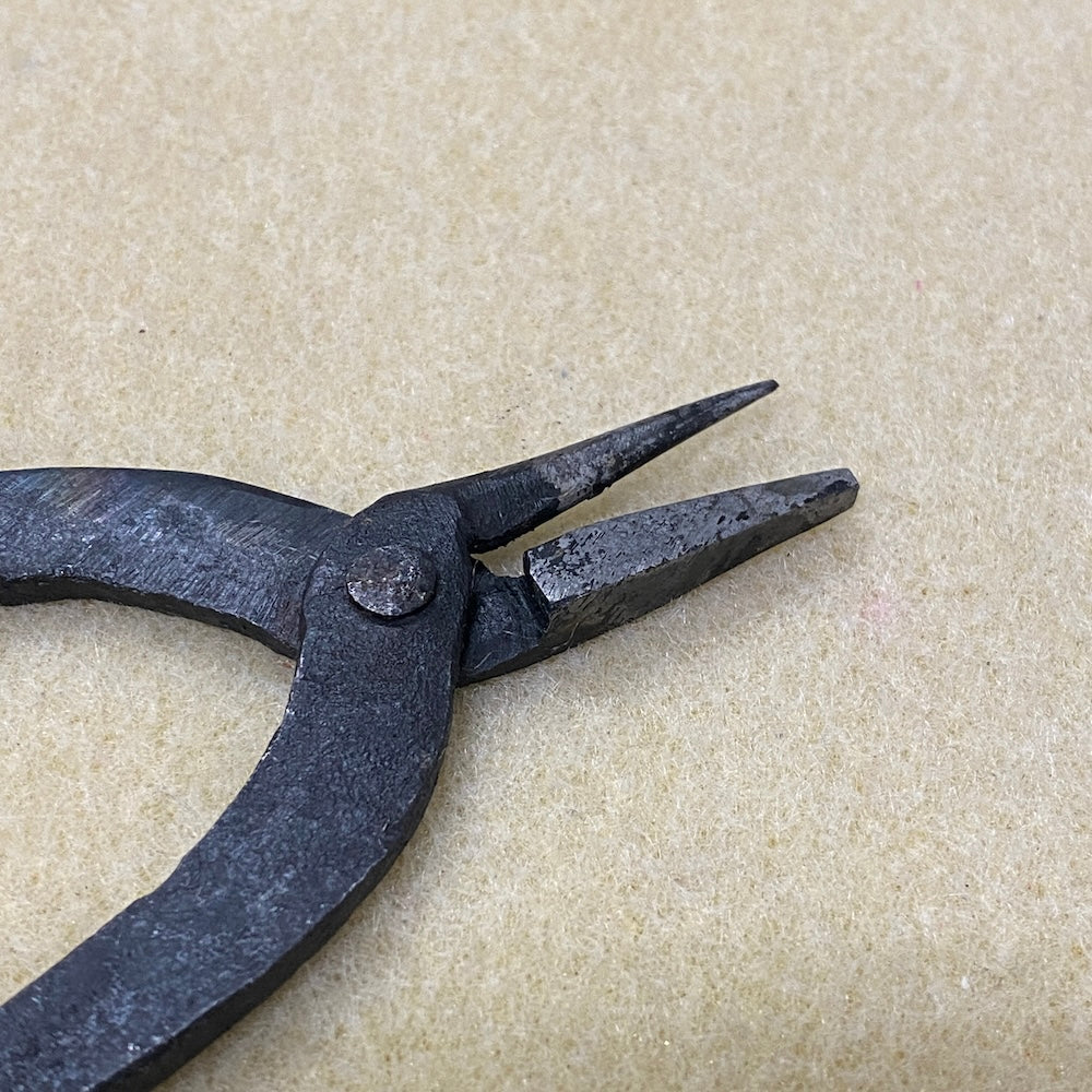 Pair of black pliers on a beige fabric background