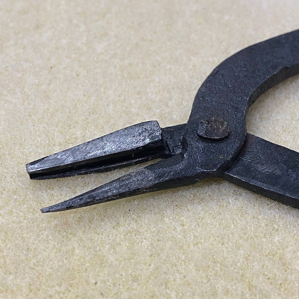Pair of black metal pliers on a beige background