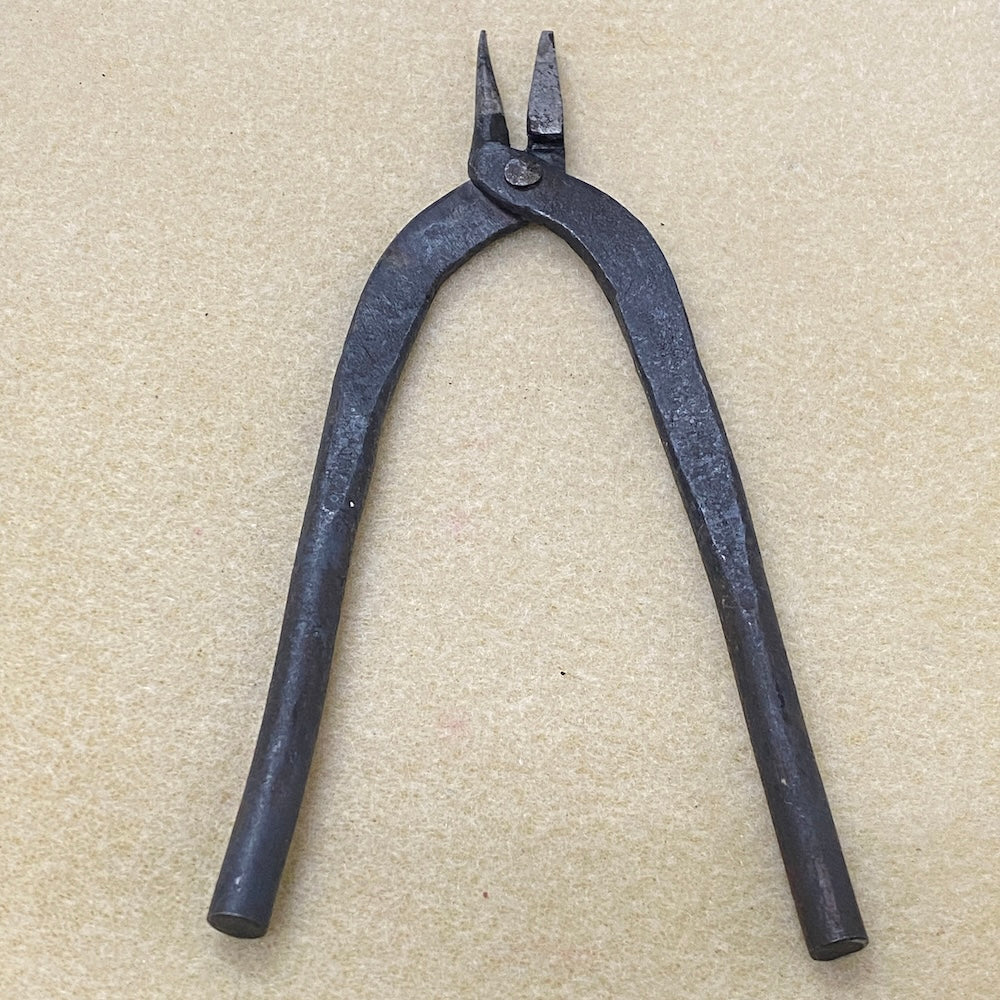 Pair of black metal pliers on a beige background