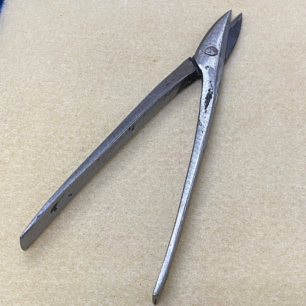 Pair of metal snipper pliers on a beige background