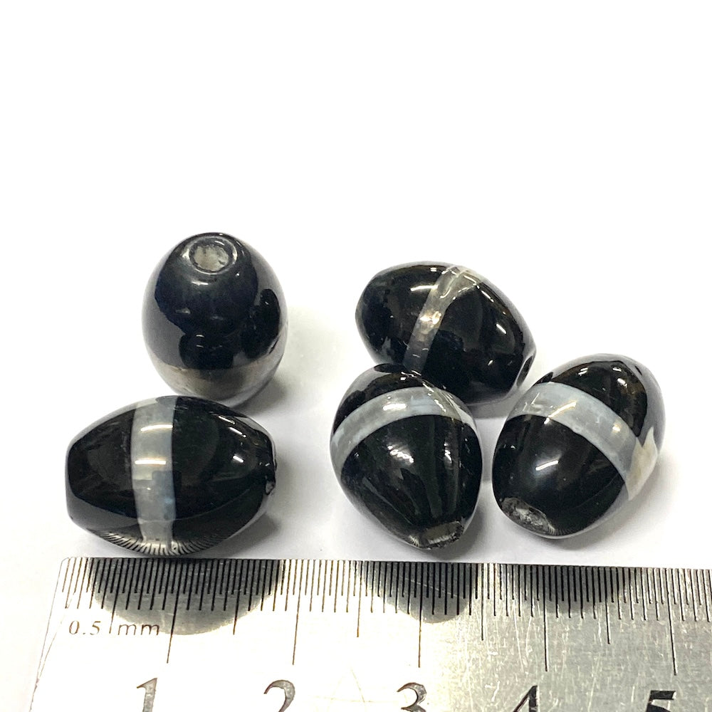 five Black and silver striped beads with a ruler for scale on a white background