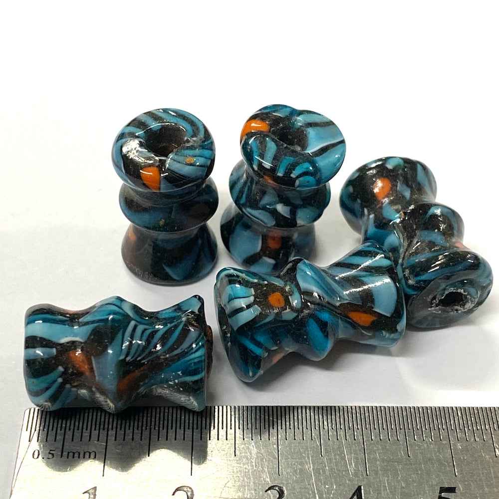 Set of blue and black striped beads with orange accents on a white background, measured against a ruler.