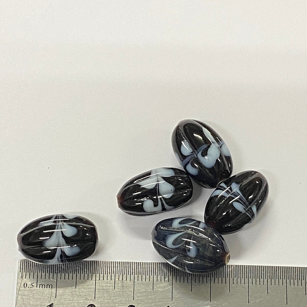 Black and white marbled stones with a ruler for scale on a white background