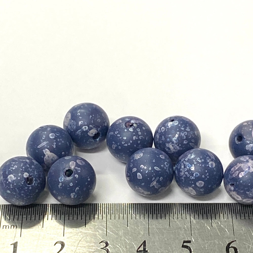 Blue speckled beads with a ruler for scale on a white background