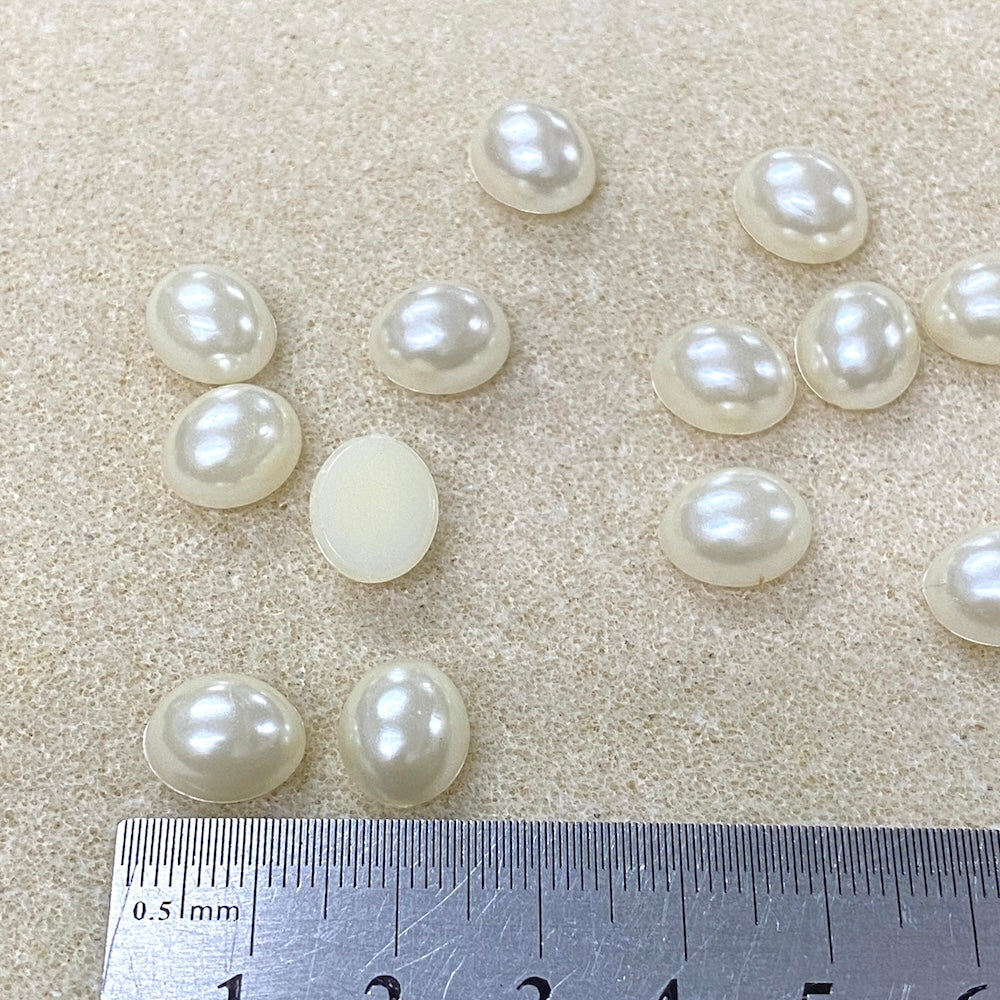 Pearls on a light brown surface with a ruler for scale.