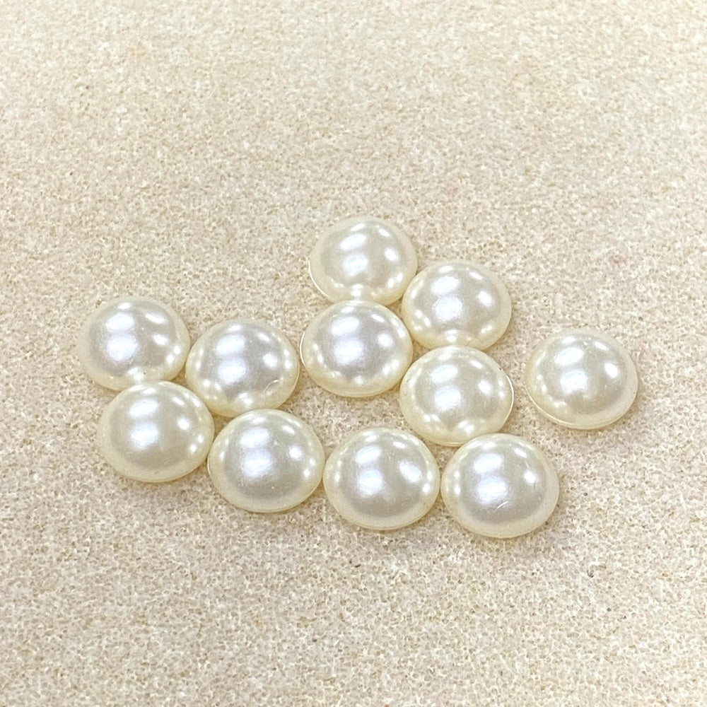 Pearl cabochons arranged on a textured beige surface