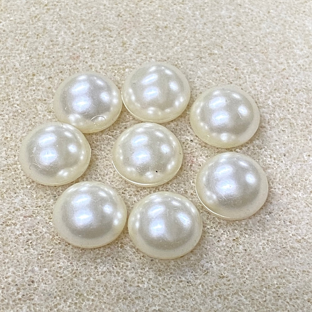 White pearl cabochons on a textured beige surface