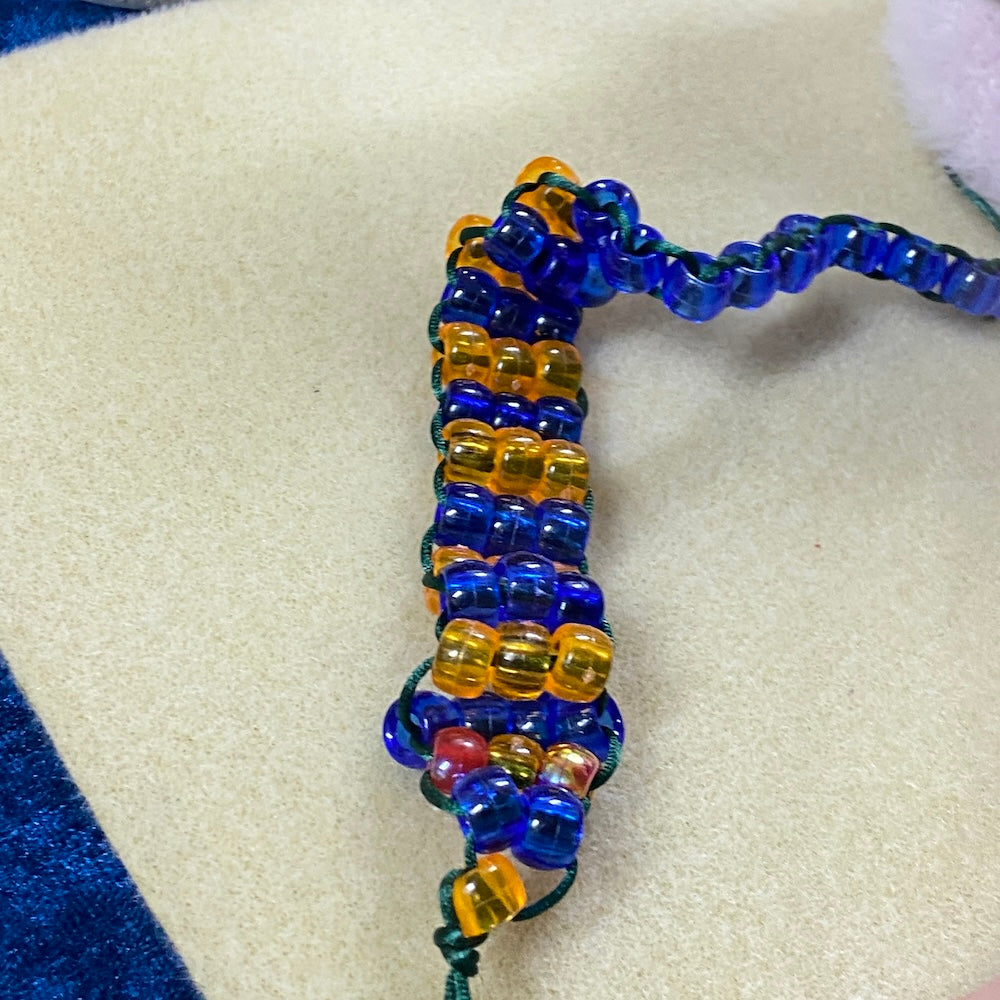 a beaded snake in blue and orange on a cream mat in the background as a sample of a project at a Bead shack children workshop