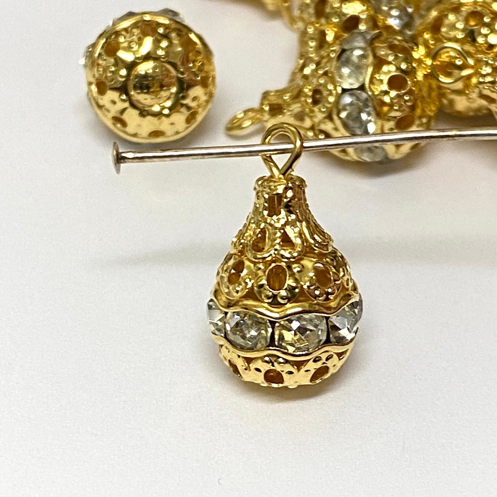 Group of gold and crystal pear shaped pendant beads on a white background