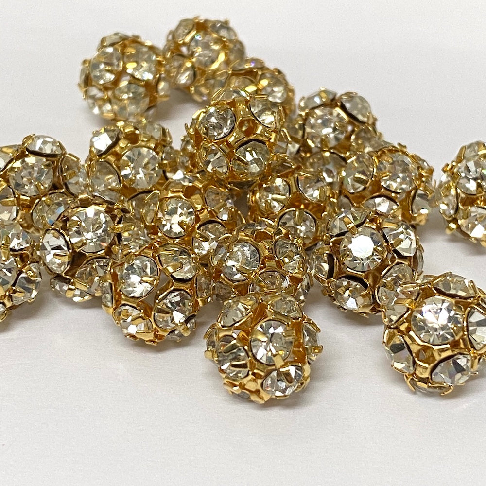 group of gold and crystal beads on a pin on a white background