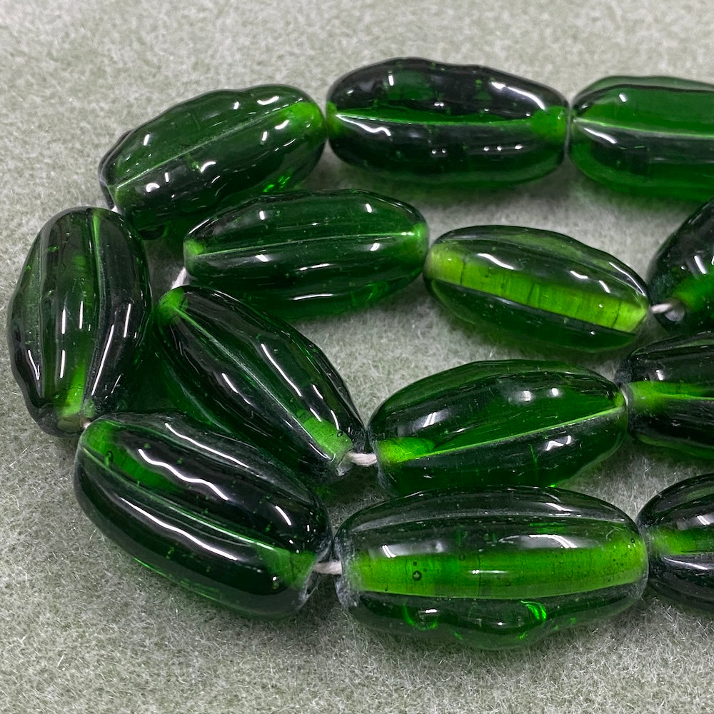 Green glass starfruit java beads on a gray surface