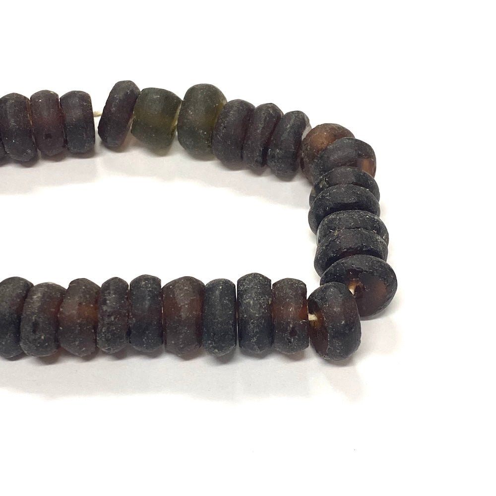 Close-up of dark brown recycled glass beads on a white background