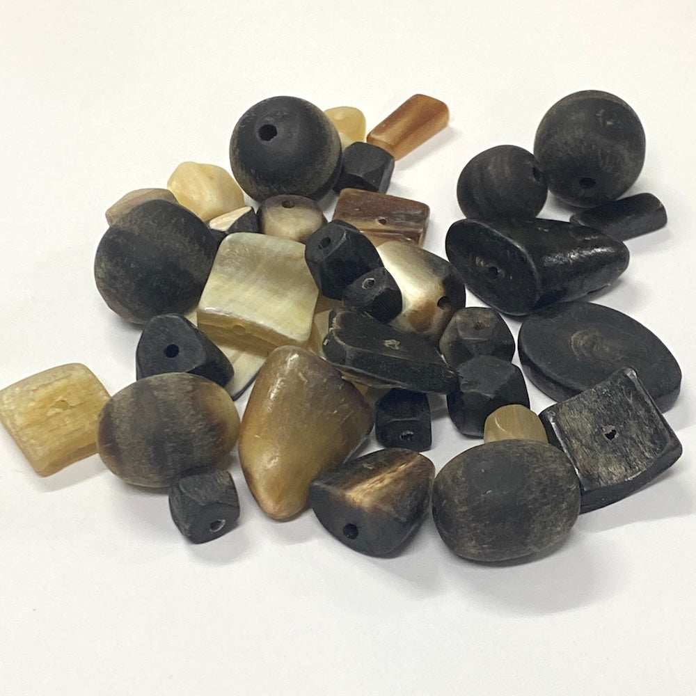 Assorted hand carved natural horn beads in cream black and brown colours on a white background