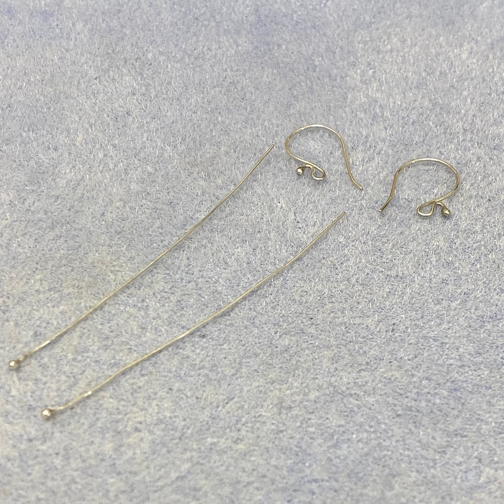 Silver earring hooks and threaders on a gray surface