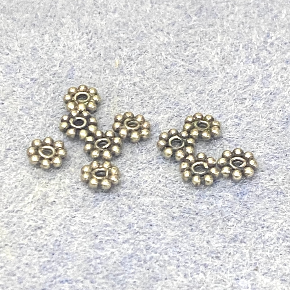 Sterling Silver floral daisy spacer beads on a light gray background