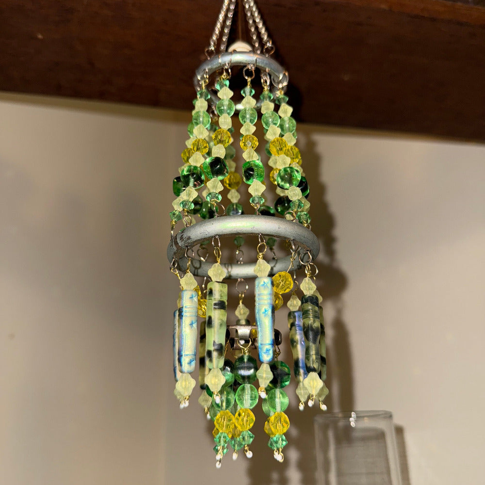 Decorative beaded hanging ornament on a wooden shelf with containers in the background.