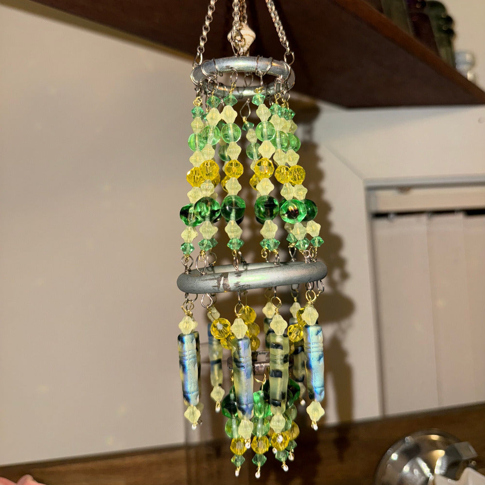 Decorative wind chime with vaseline uranium green and yellow beads hanging indoors.