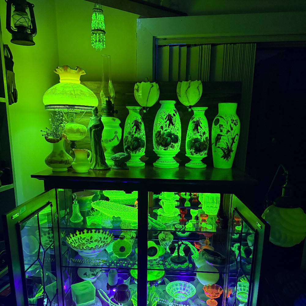 Glowing vases and decorative items in a cabinet under UV light
