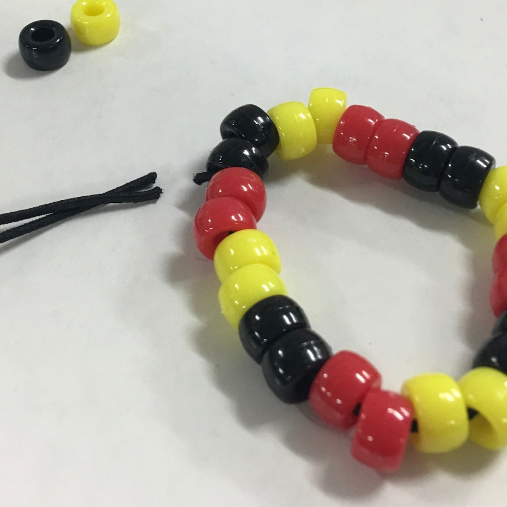 Beaded bracelet with red, yellow, and black beads on a white background