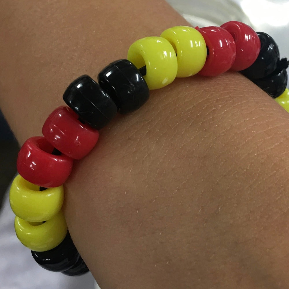 Colorful beaded bracelet on a wrist with red, yellow, and black beads.