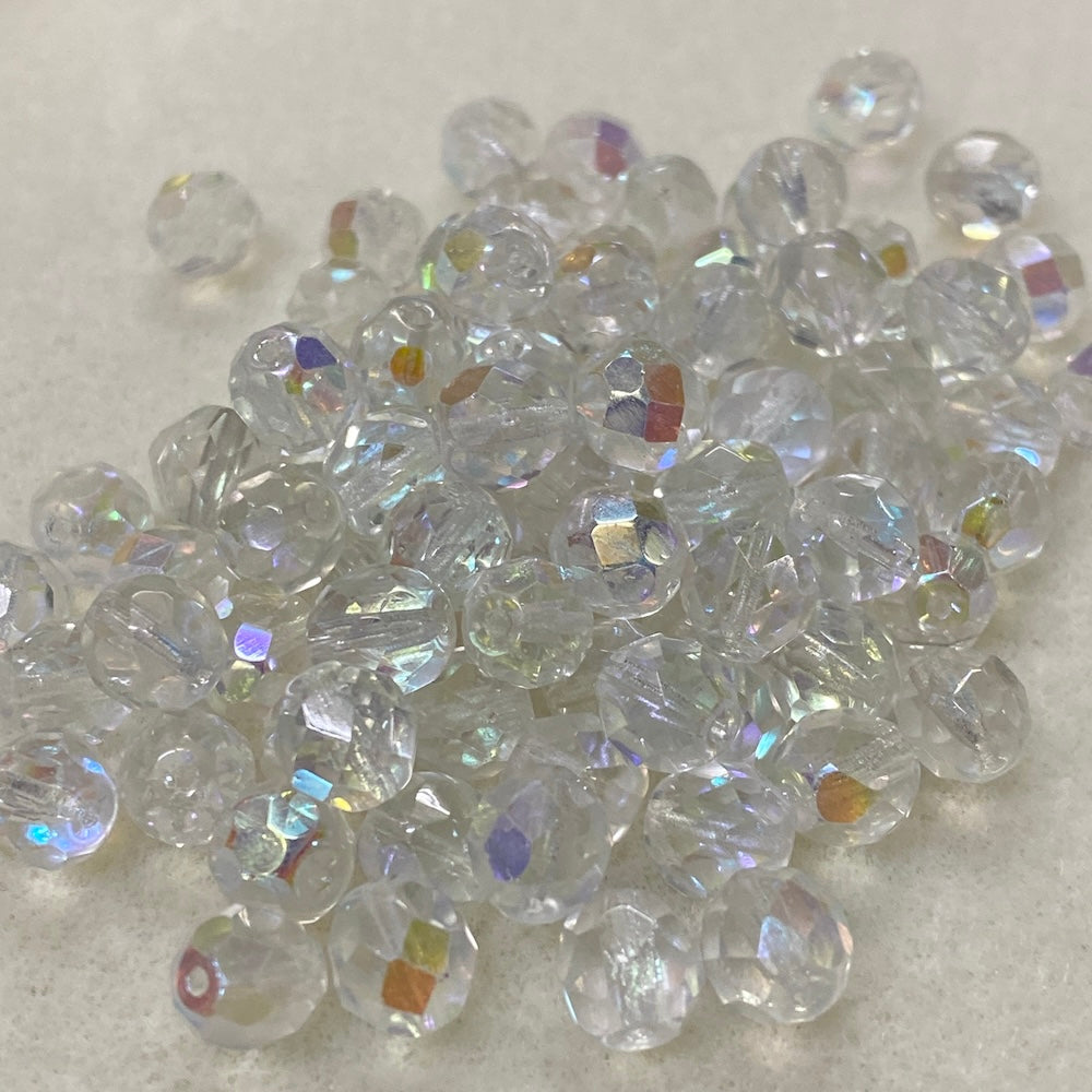 Clear fire polish crystal glass beads with iridescent flash on a light gray background
