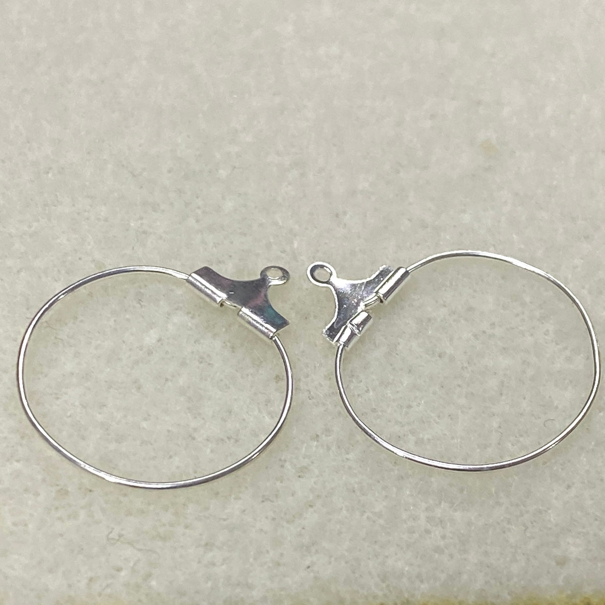Pair of silver hoop earrings on a light gray background
