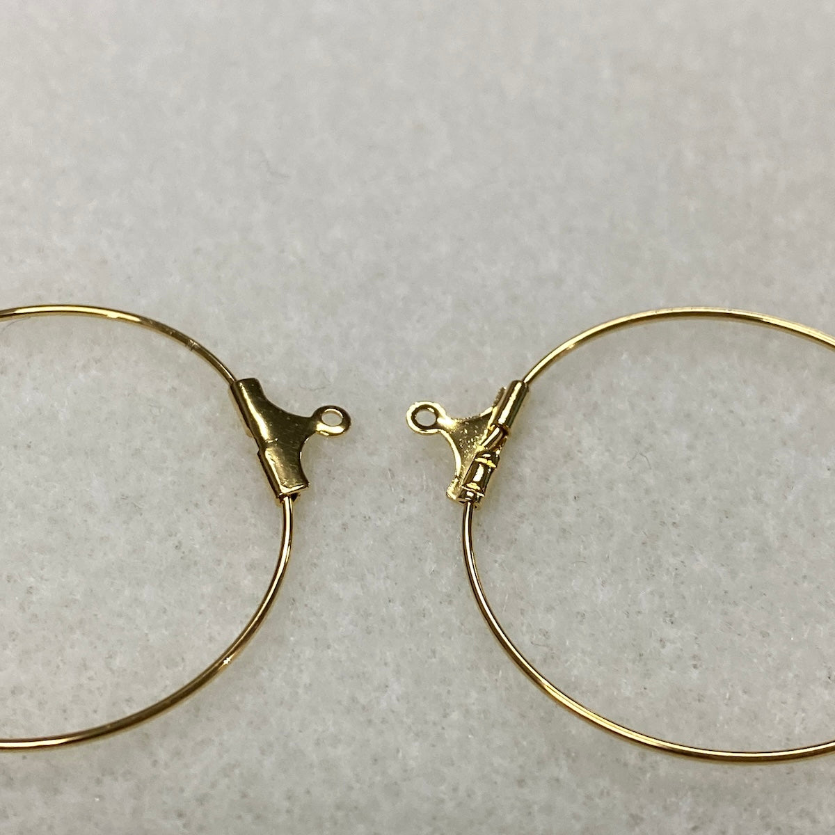 Gold hoop earrings with clasp on a light gray background