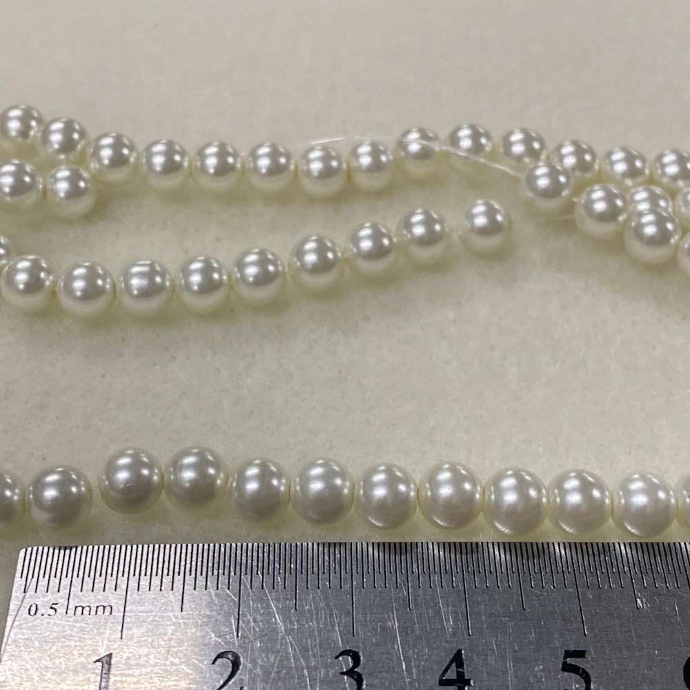 Two strands of pearls with a ruler for scale on a light gray background