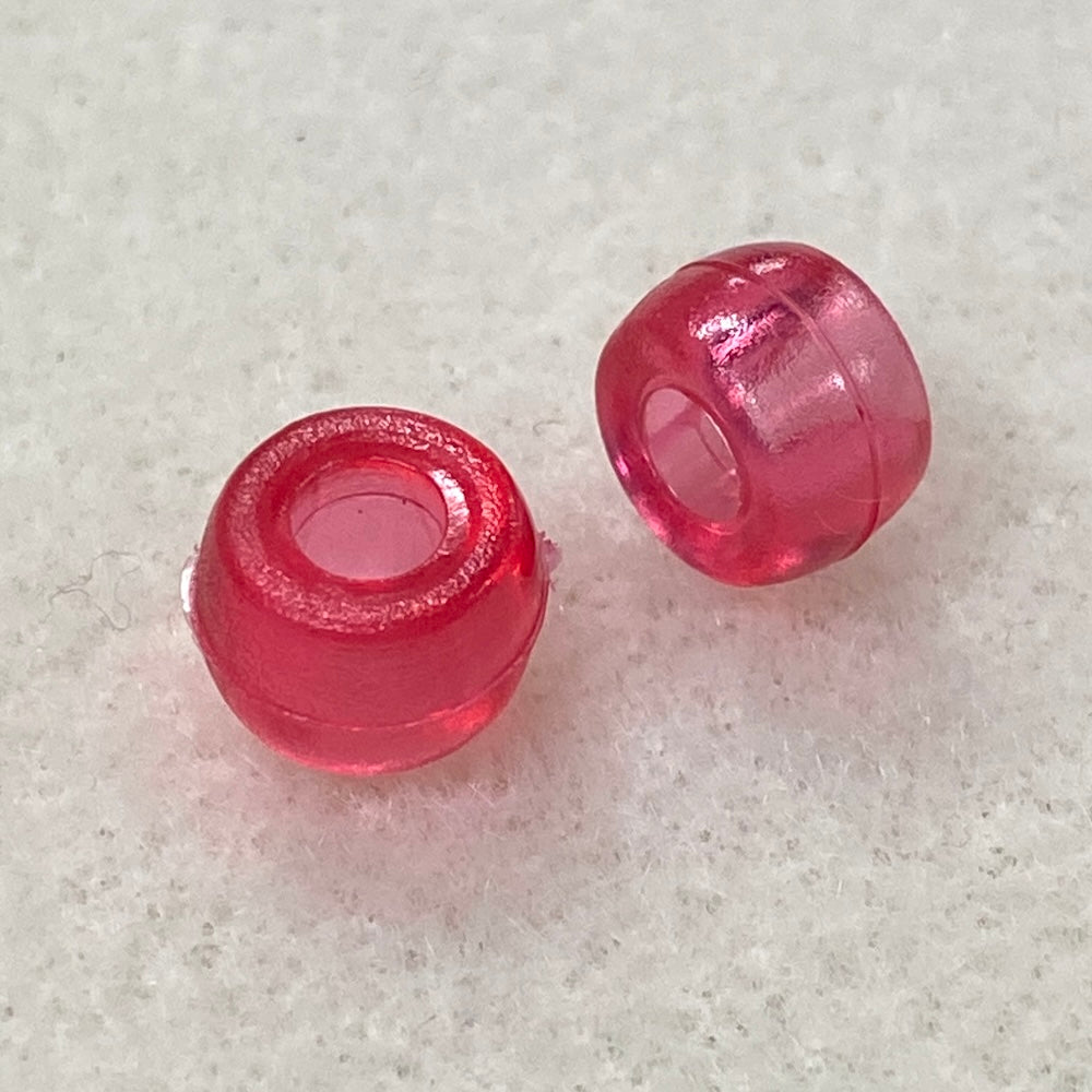 Two pink transparent beads on a textured gray surface