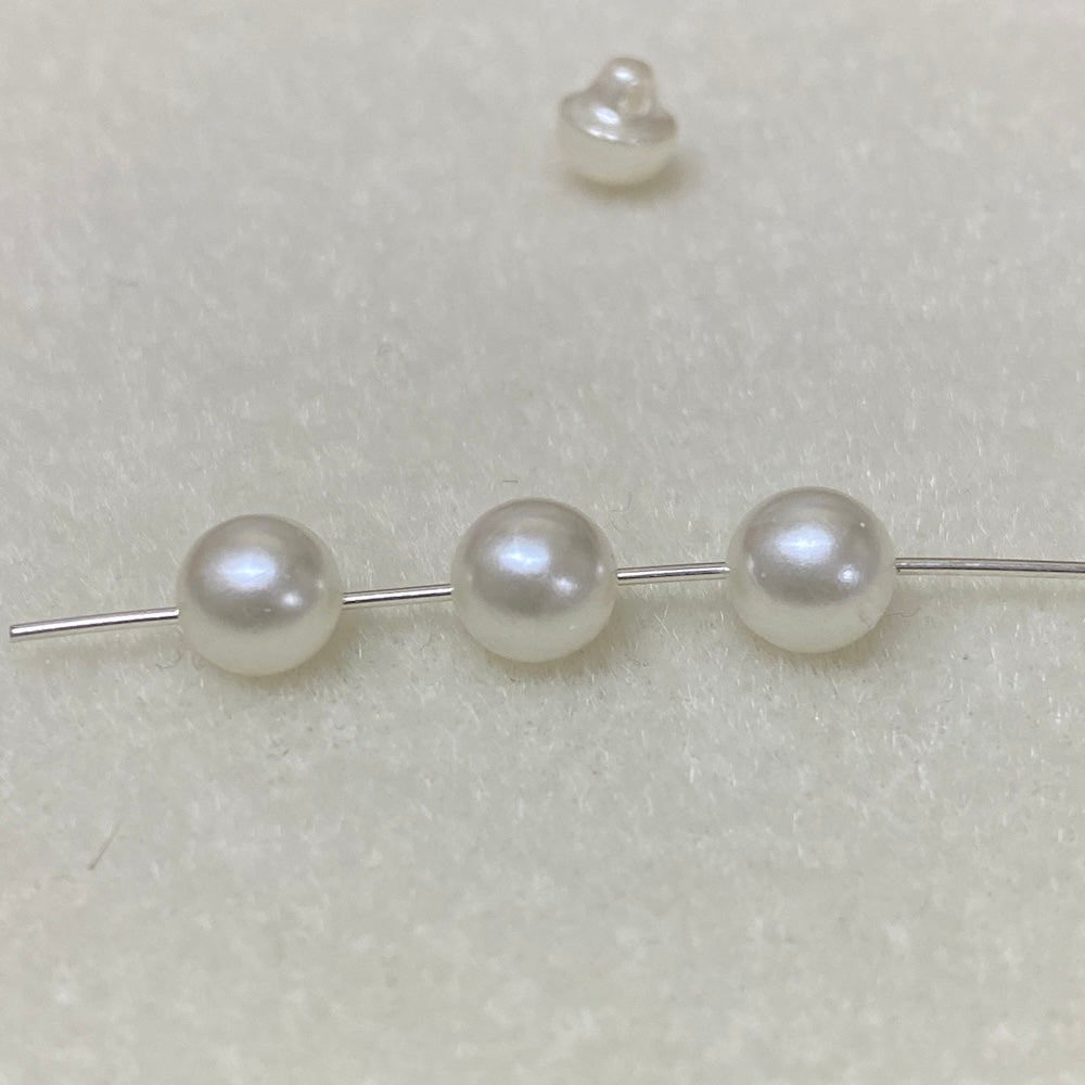 Pearl buttons on a thin metal rod against a light gray background