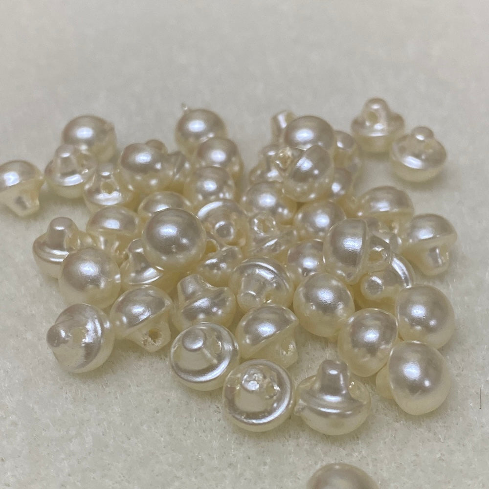 Collection of cream pearl buttons on a light gray background