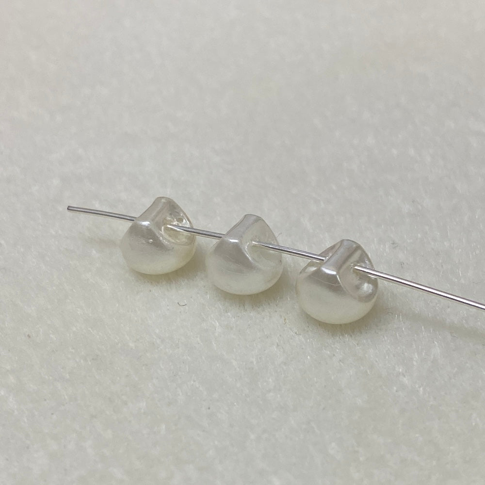 Three pearl buttons on a thin wire against a light gray background