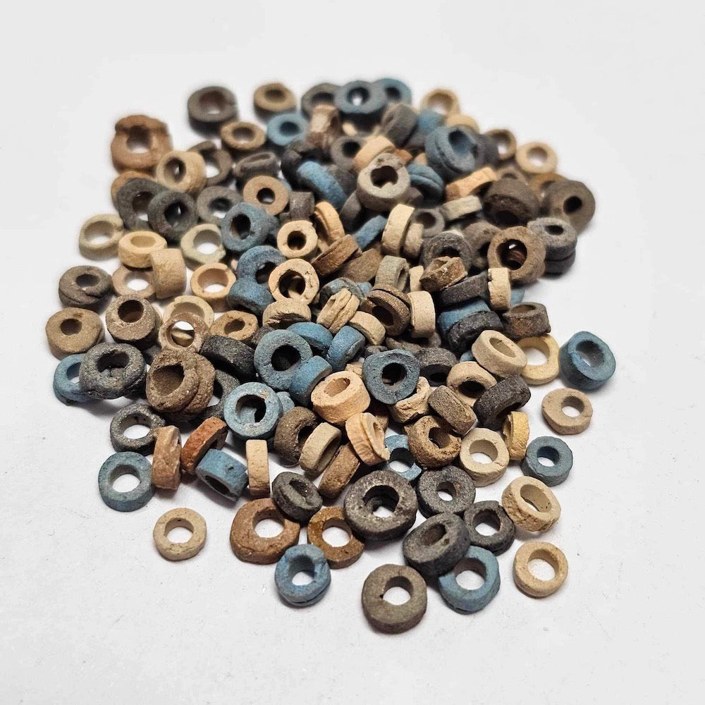 A collection of colored vintage faience beads arranged in a pile, with varying shapes colors and textures.