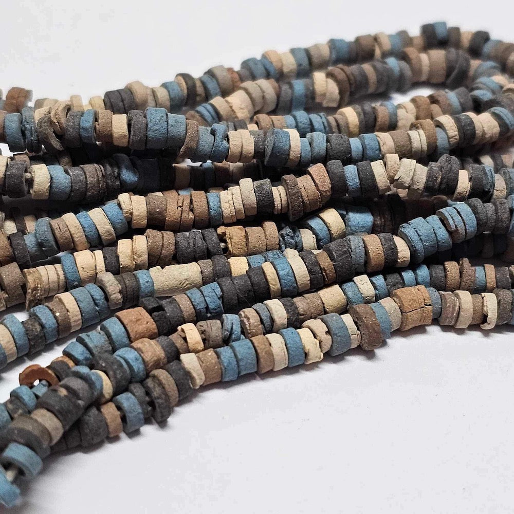 A strand of vintage faience clay beads in various shades of blue, black, cream, and brown, knotted on a string.
