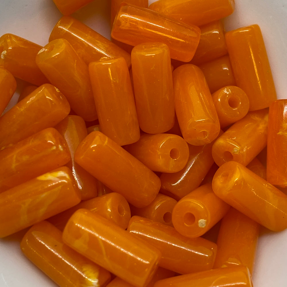 A collection of orange, cylindrical vintage beads with a marbled effect.