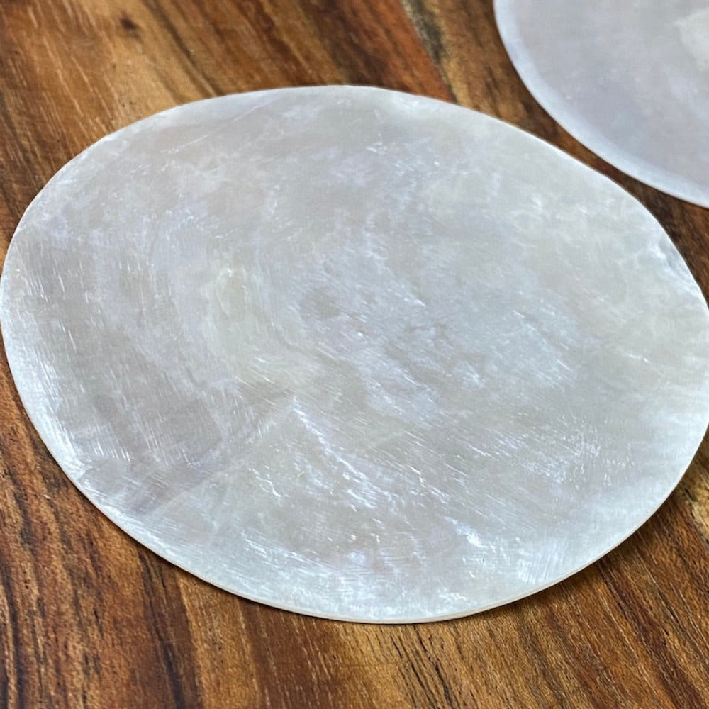 white, round capiz shell disc placed on a wooden surface used for wedding name place settings, bonbonniere, artwork and craft items displayed on a wooden surface