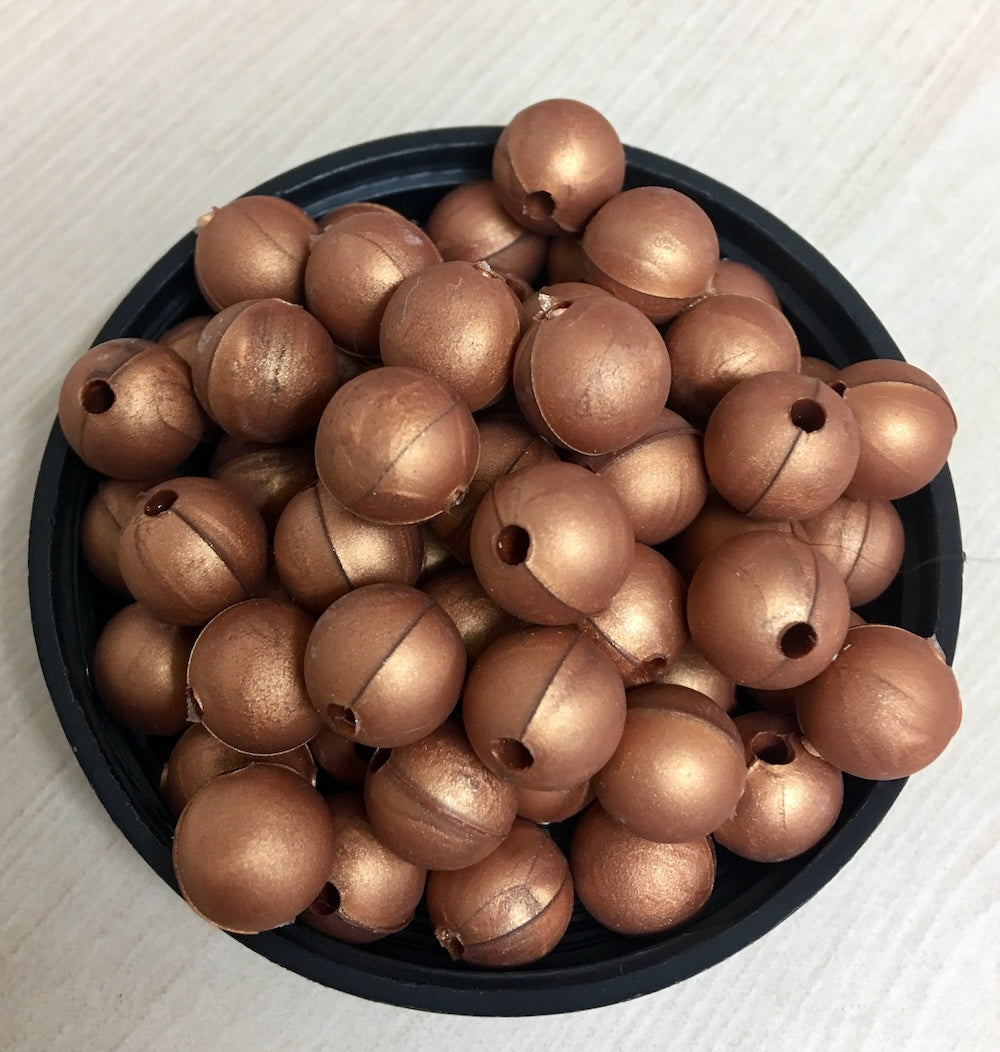 A black container filled with copper round silicone beads, with a threading hole visible on each bead.