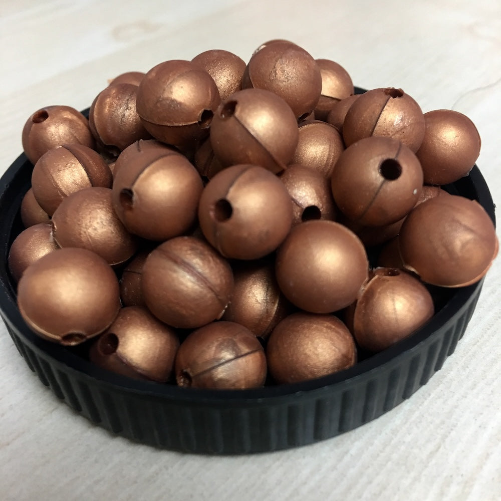 A black container filled with copper round silicone beads, with a threading hole visible on each bead.