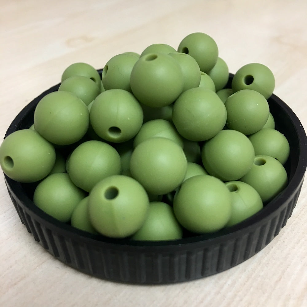 A black container filled with olive green round silicone beads, with a threading hole visible on each bead.
