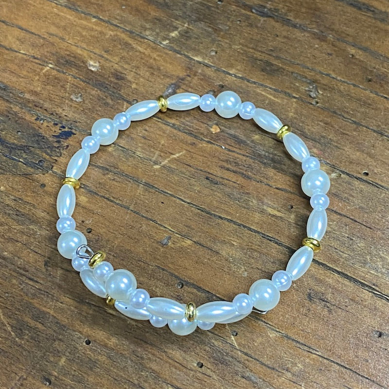 Example of a pearl and gold necklace made at a Bead Shack workshop on a wooden surface