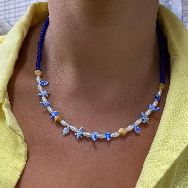 Sample necklace idea worn on a person's neck with pearls wood and turtle and leaf beads in blue
