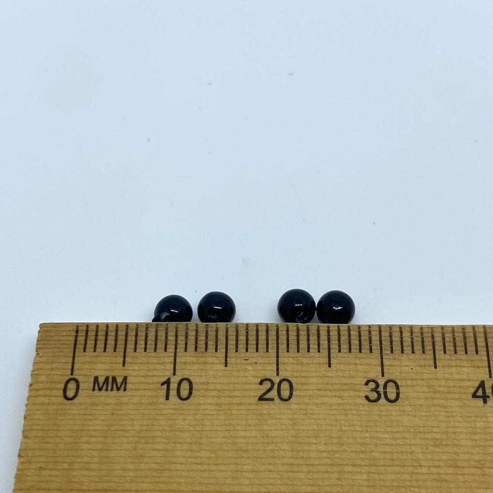 Four black beads on a wooden ruler against a white background