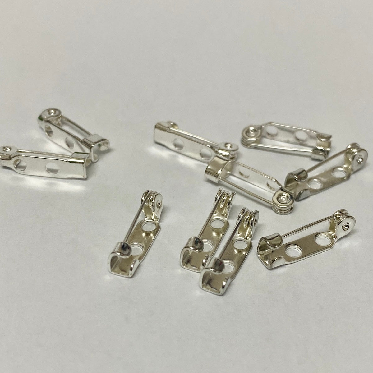silver brooch backs displayed on a white surface
